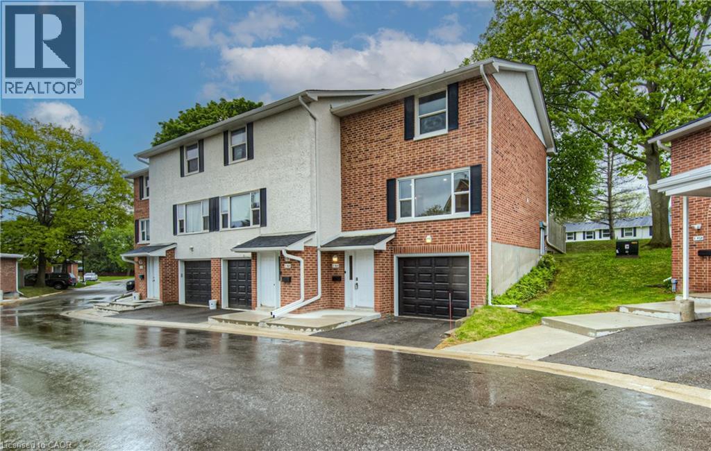 View of property with a garage, driveway, brick siding, and cooling unit - 425 Keats Way Unit# 4, Waterloo, ON - Outdoor