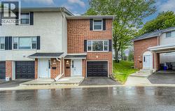 View of property featuring driveway, an attached garage, brick siding, and stucco siding -