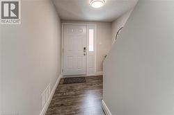 Foyer with a textured ceiling, dark wood-style flooring, and baseboards -