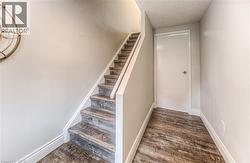 Stairs with baseboards, wood finished floors, and a textured ceiling -