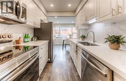 Kitchen featuring stainless steel appliances, a sink, dark wood-style floors, recessed lighting, and white cabinetry -