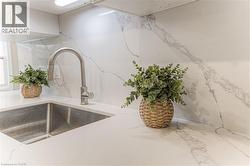 Kitchen view of a sink and light stone counters -