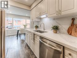 Kitchen with dishwasher, a sink, freestanding refrigerator, dark wood-style flooring, and decorative backsplash -
