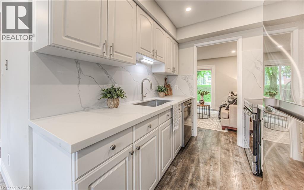 Kitchen featuring a sink, stainless steel dishwasher, dark wood-style flooring, white cabinetry, and tasteful backsplash - 425 Keats Way Unit# 4, Waterloo, ON - Indoor Photo Showing Kitchen With Upgraded Kitchen