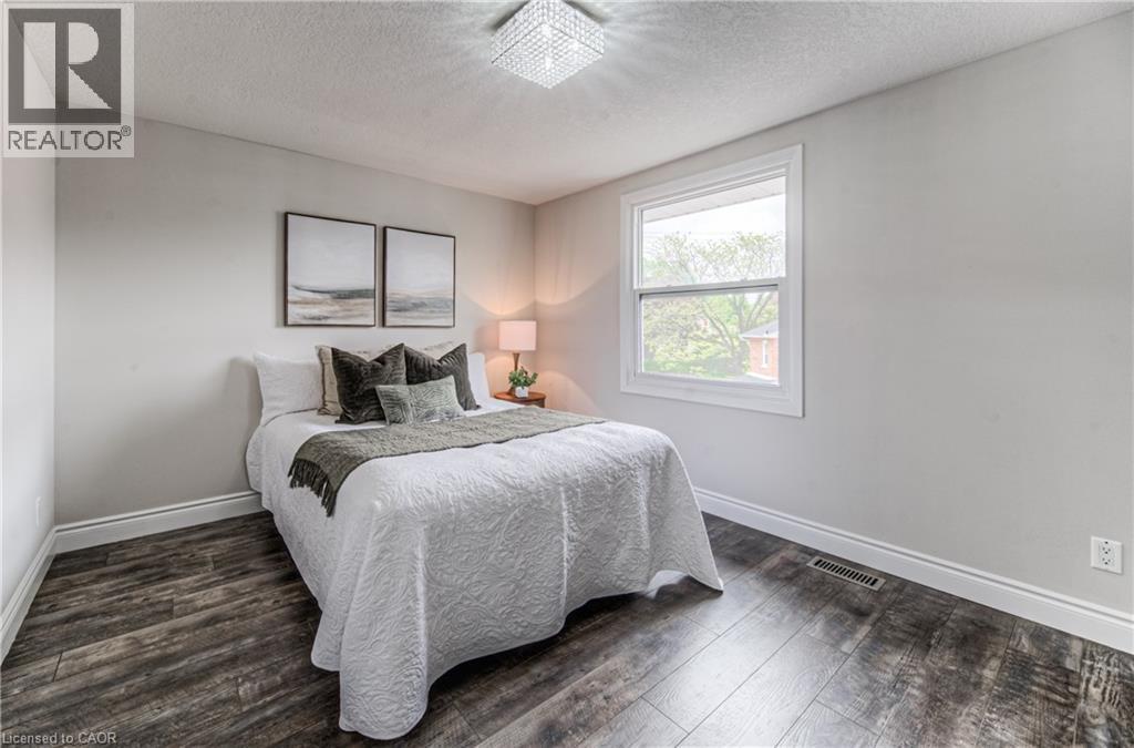 Bedroom featuring a textured ceiling, dark wood-type flooring, and baseboards - 425 Keats Way Unit# 4, Waterloo, ON - Indoor Photo Showing Bedroom
