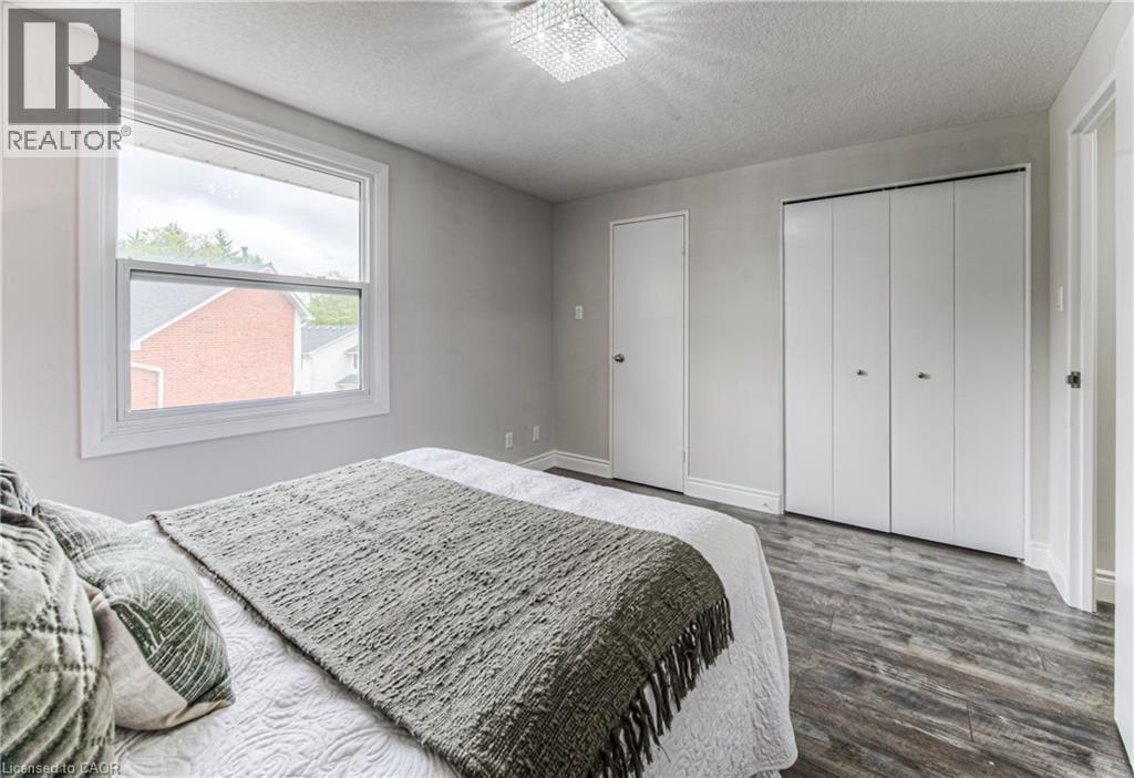 Bedroom featuring dark wood finished floors, a textured ceiling, a closet, and baseboards - 425 Keats Way Unit# 4, Waterloo, ON - Indoor Photo Showing Bedroom