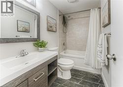 Bathroom with toilet, vanity, and shower / bath combination with curtain -