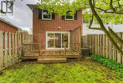 Back of house featuring a fenced backyard, brick siding, central AC, and a deck -
