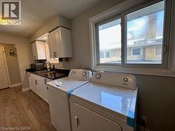 Laundry room with dark wood finished floors, washer and clothes dryer, and cabinet space -