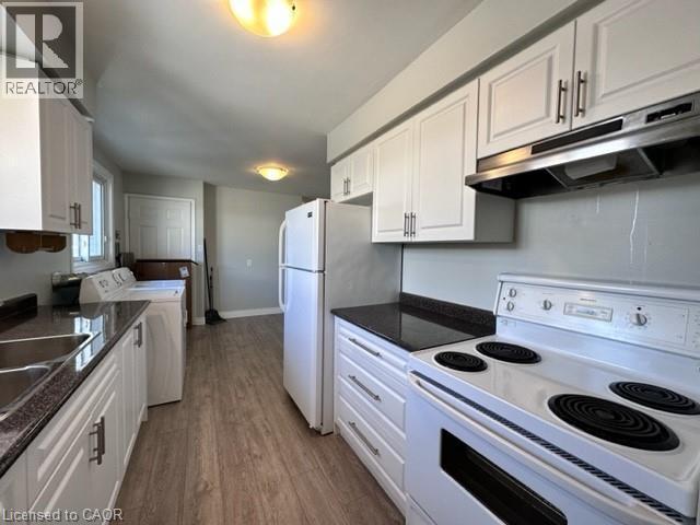 Kitchen featuring white appliances, white cabinetry, under cabinet range hood, and dark wood-style flooring - 121 Roberts Crescent Unit# Upper, Kitchener, ON - Indoor Photo Showing Kitchen