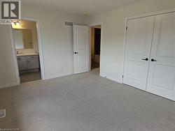 Unfurnished bedroom with light colored carpet, connected bathroom, and a closet -