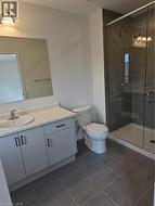 Full bathroom featuring vanity, a stall shower, and dark tile patterned flooring -