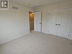 Unfurnished bedroom with attic access, carpet flooring, and a closet -