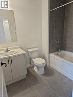 Full bathroom featuring bathing tub / shower combination, vanity, and dark tile patterned floors -