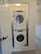 Washroom featuring stacked washer / drying machine and carpet floors -