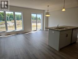 Kitchen with hanging light fixtures, dark wood finished floors, dishwashing machine, open floor plan, and a center island with sink -