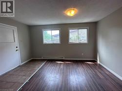 Unfurnished room featuring a textured ceiling, hardwood / wood-style floors, and a baseboard radiator -