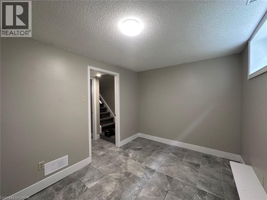 Unfurnished room with a textured ceiling and stairway - 17 St Leger Street, Kitchener, ON - Indoor Photo Showing Other Room