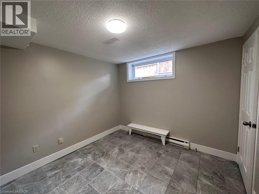 Empty room featuring a textured ceiling and baseboard heating - 17 St Leger Street, Kitchener, ON - Indoor Photo Showing Other Room