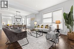 Living room with dark wood-type flooring, plenty of natural light, and a chandelier -