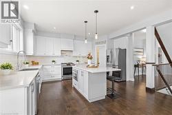 Kitchen featuring stainless steel appliances, a breakfast bar area, pendant lighting, white cabinetry, and a center island -