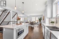 Kitchen featuring white cabinets, pendant lighting, appliances with stainless steel finishes, dark wood-style floors, and backsplash -