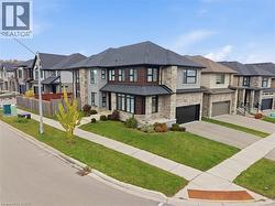 View of front facade with stone siding, a front lawn, a residential view, driveway, and an attached garage -