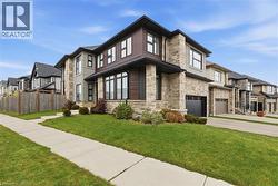View of front of house with stone siding, a residential view, an attached garage, and driveway -