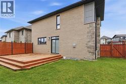 Rear view of house with a wooden deck, a fenced backyard, brick siding, and a gate -