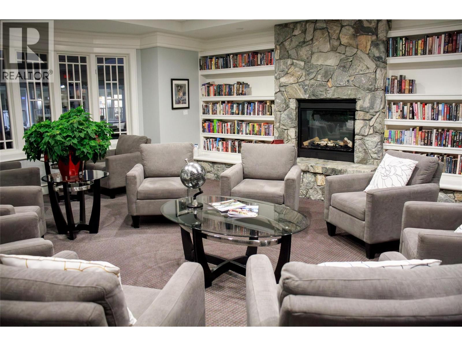 reading nook and many books and puzzles to borrow and share - 3897 Gallaghers Grange, Kelowna, BC - Indoor Photo Showing Living Room With Fireplace