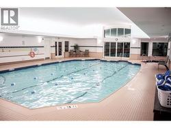 large indoor pool with hot tub and fitness equipment -