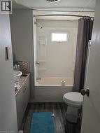 Bathroom featuring vanity, dark wood finished floors, shower / bath combo, and backsplash -