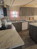 Kitchen featuring light countertops, decorative backsplash, white appliances, beamed ceiling, and dark wood-style flooring -