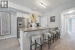 Kitchen with white cabinetry, light wood-style floors, stainless steel fridge with ice dispenser, and a kitchen bar -