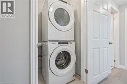 Washroom with estacked washer and dryer and light wood finished floors -
