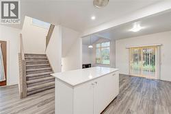 Kitchen featuring white cabinetry, light countertops, light wood-type flooring, a center island, and decorative light fixtures -