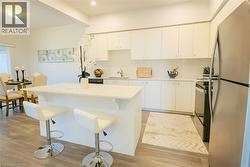 Kitchen with freestanding refrigerator, light countertops, white cabinets, a center island, and black electric range -