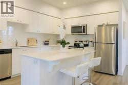 Kitchen featuring appliances with stainless steel finishes, light wood-type flooring, decorative backsplash, and white cabinets -