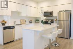 Kitchen featuring appliances with stainless steel finishes, backsplash, light wood-style floors, a center island, and white cabinetry -