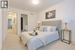 Bedroom featuring connected bathroom and light colored carpet -