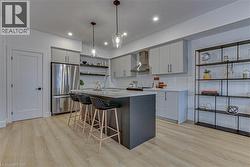 Kitchen with open shelves, a breakfast bar, freestanding refrigerator, pendant lighting, and gray cabinetry -