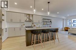 Kitchen with open shelves, tasteful backsplash, decorative light fixtures, a breakfast bar, and light wood-type flooring -