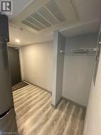 Basement with light wood finished floors and freestanding refrigerator -