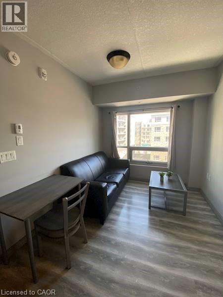 Living room with a textured ceiling and wood finished floors - 275 Larch Street Unit# F313, Waterloo, ON - Indoor