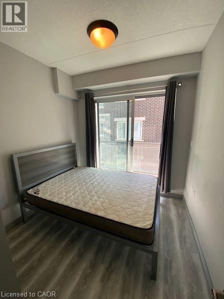 Bedroom with wood finished floors and a textured ceiling - 275 Larch Street Unit# F313, Waterloo, ON - Indoor