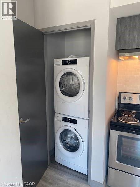 Laundry room with stacked washer / dryer and light wood-type flooring - 275 Larch Street Unit# F313, Waterloo, ON - Indoor Photo Showing Laundry Room