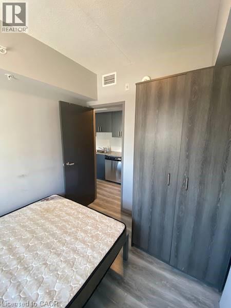 Bedroom featuring wood finished floors, a closet, and a textured ceiling - 275 Larch Street Unit# F313, Waterloo, ON - Indoor Photo Showing Bedroom