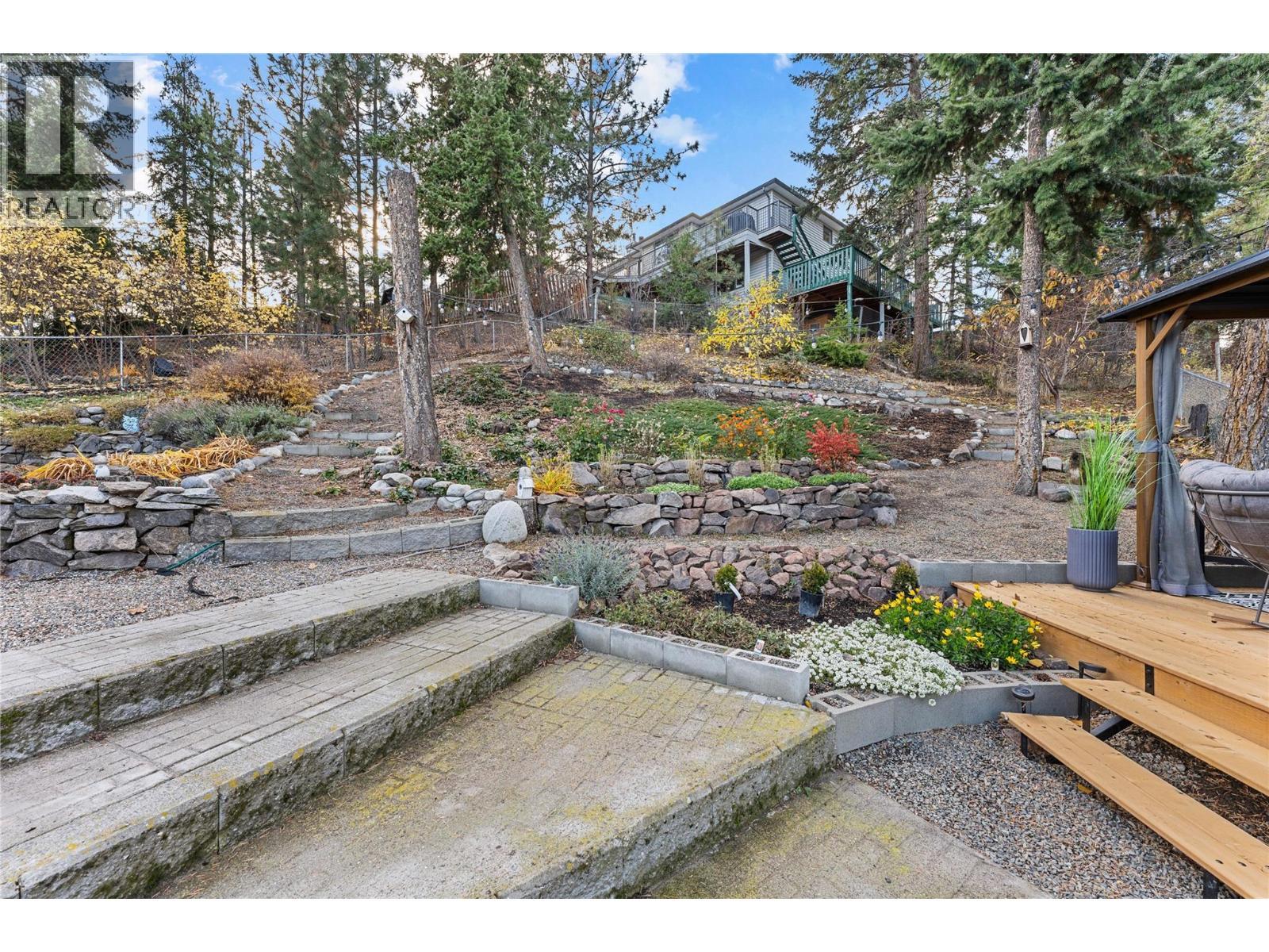 Tiered landscaping and fruit trees provide a lush backdrop in spring and summer. - 3380 Mciver Road, West Kelowna, BC - Outdoor