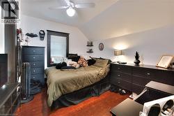 Bedroom with wood finished floors, vaulted ceiling, and a ceiling fan -