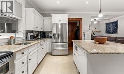 Kitchen featuring white cabinets, stainless steel appliances, tasteful backsplash, light stone countertops, and crown molding -